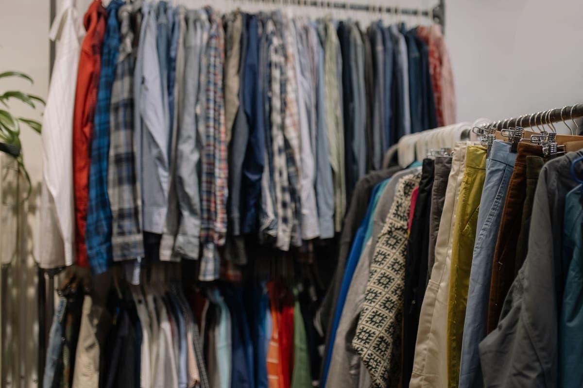 Portants de vêtements d'occasion serrés les uns contre les autres dans une friperie