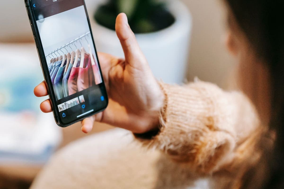 Vendeuse examinant les photos de ses annonces de vêtements sur son téléphone