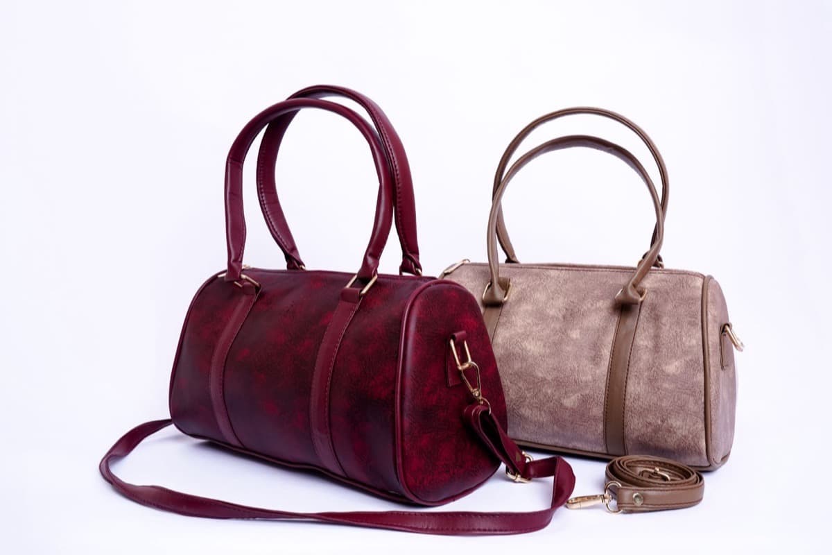 Deux sacs à main en cuir, bordeaux et taupe, photographiés sur fond studio blanc
