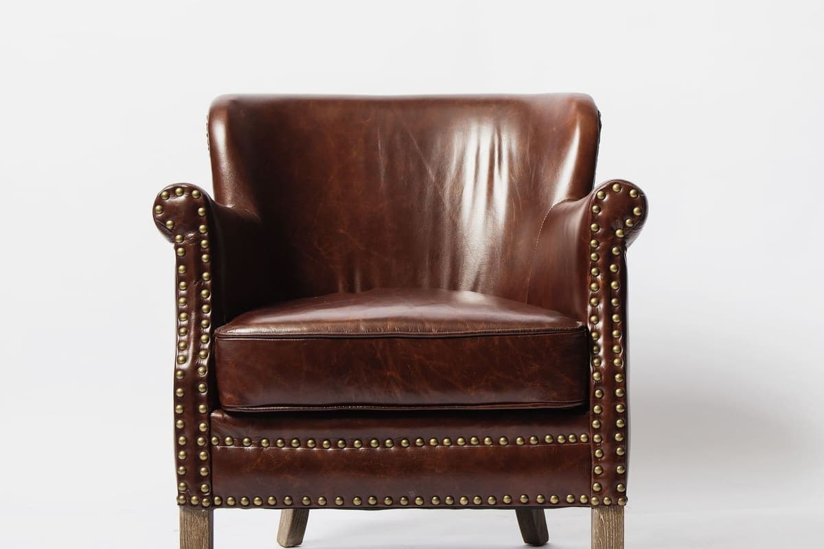 Fauteuil club en cuir brun photographié sur fond clair et dégagé, prêt pour une annonce